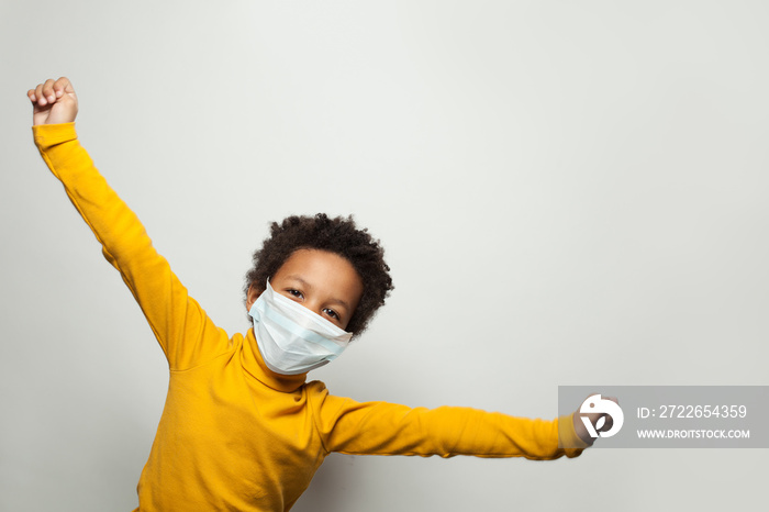 Portrait of funny black child boy in medical protective face mask having fun