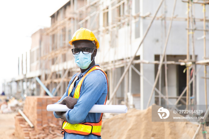 African American construction worker on building site. wearing surgical face mask during coronavirus covid and flu outbreak