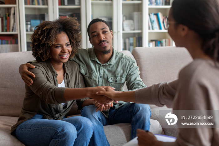 Happy black couple shaking family counselor hand, successful marital therapy