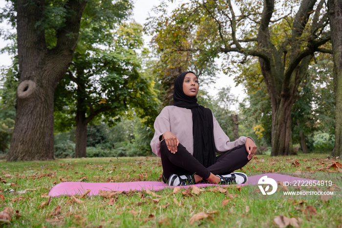 Woman in hijab meditating in park