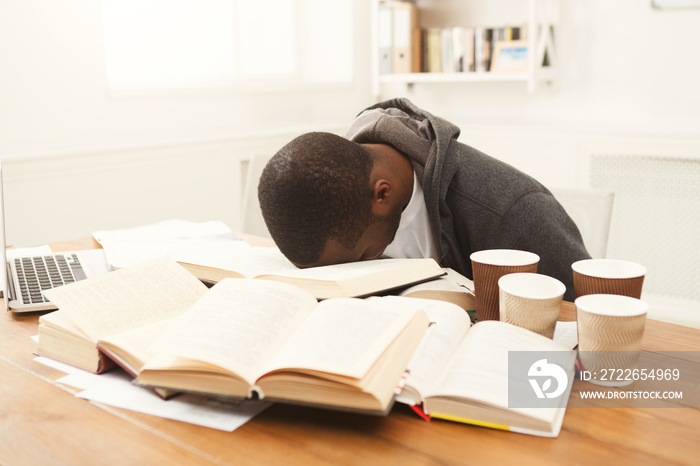 Black male student studying at table full of books