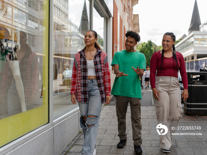 Friends walking on sidewalk in city