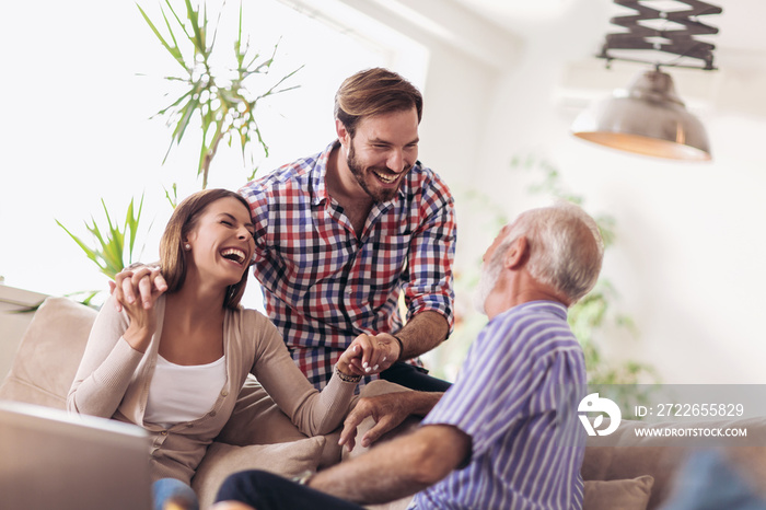 Young couple talking with their senior father at home