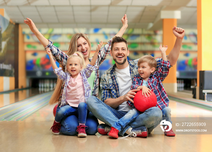 Happy family sitting on floor in bowling club