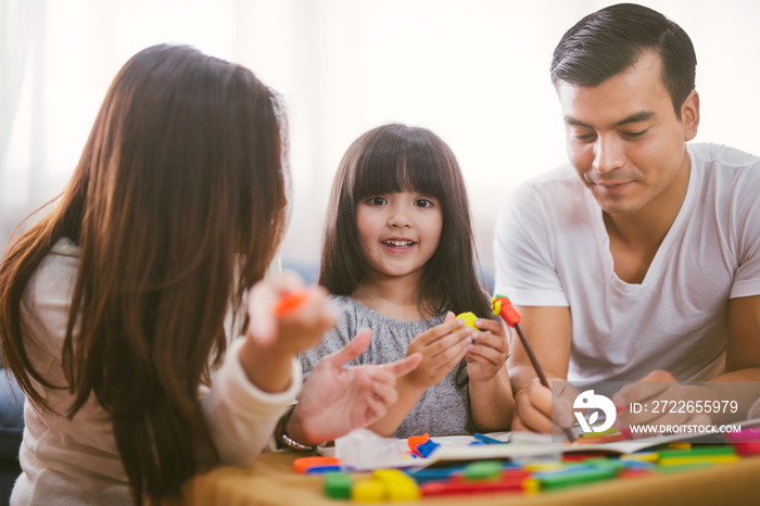 Portrait of happy family daughter girl is learning to use colorful play dough blocks toy together with parent