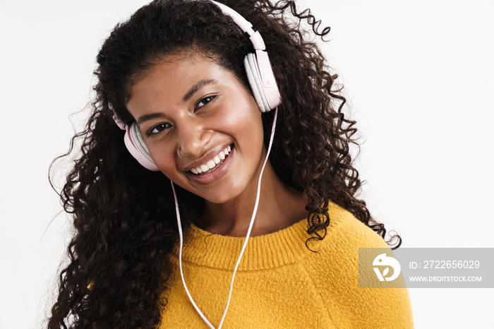 Positive young african girl listening music with heaphones