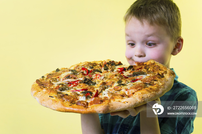 funny boy eating a big pizza on a bright yellow background