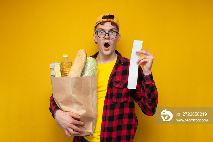 rising prices for groceries, guy buyer holds package of groceries and is surprised at the high prices, shocked shopper