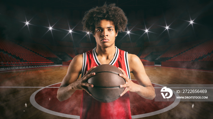 Young African American boy with basketball in the middle of the stadium