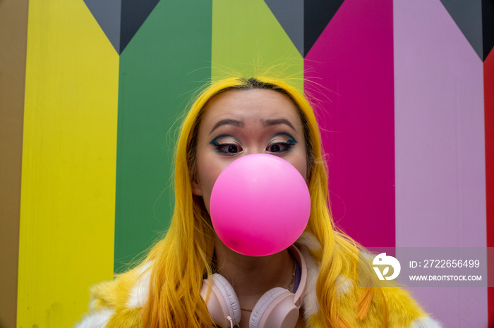 Young woman with yellow hair blowing bubble gum