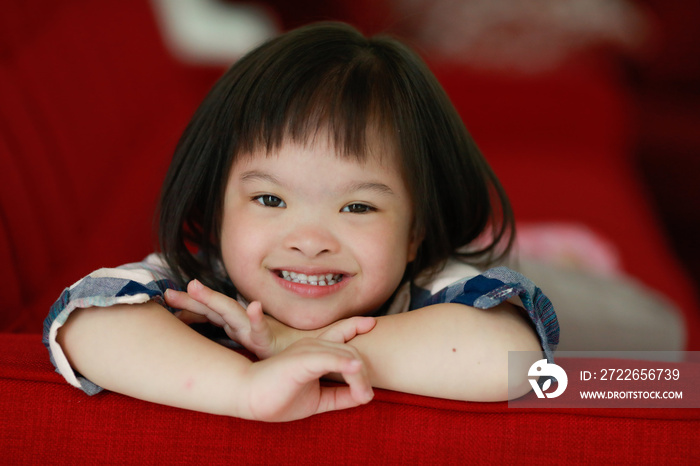 Portrait of a down syndrome baby girl smiling with happiness and play with camera