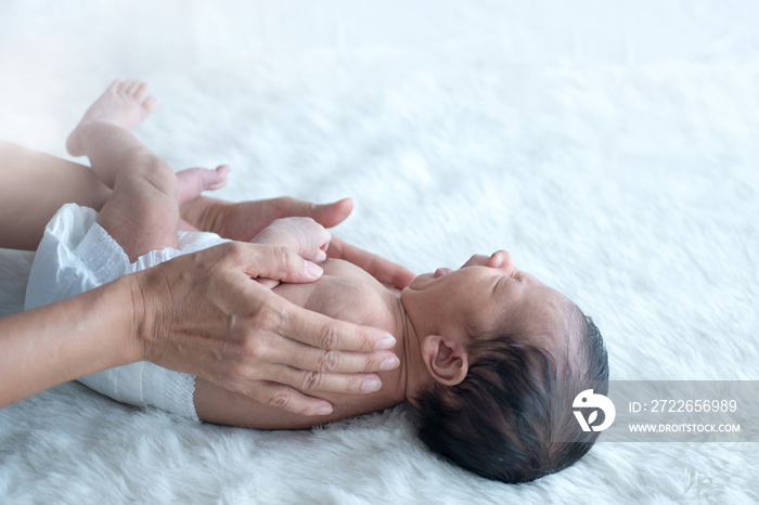 Hands of mother take care her newborn baby on white bed, massage and exercises for little newborn baby, Asian newborn baby,