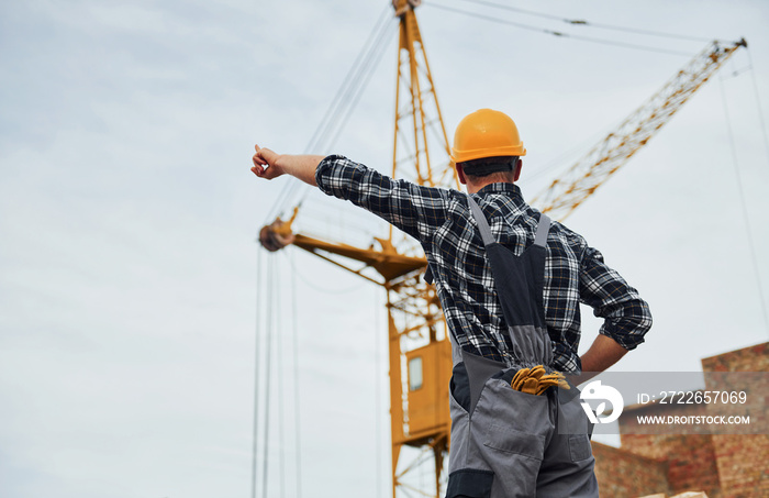 Communicates with the crane driver. Construction worker in uniform and safety equipment have job on building