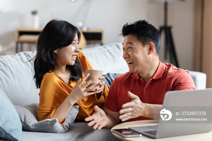 Cheerful korean couple planning vacation, using laptop