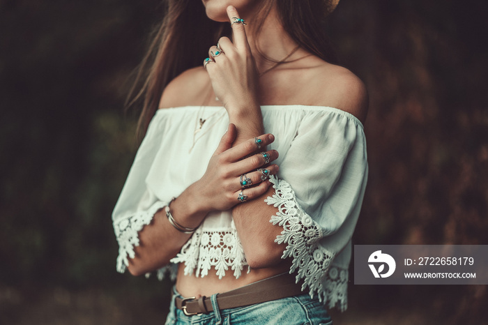 Fashionable brunette boho chic woman in a white short blouse and with silver turquoise jewelry. Boho fashion. Stylish girl wearing silver rings with turquoise stone in hippie style.