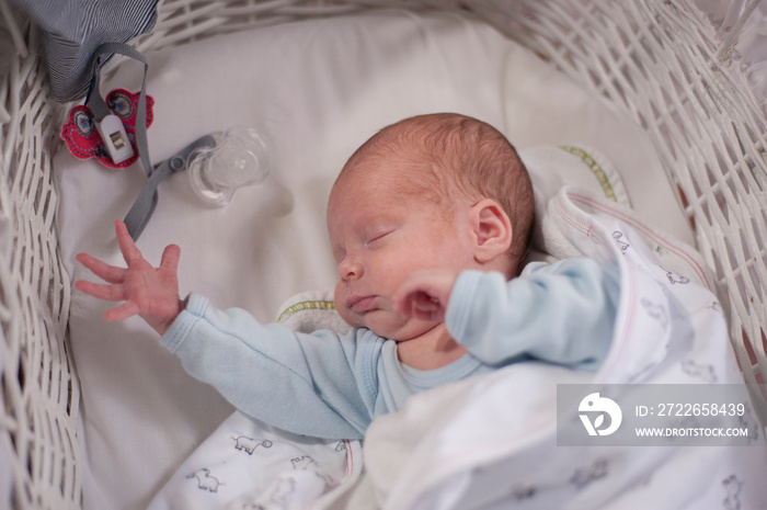 A premature baby sleeps on a moses basket.