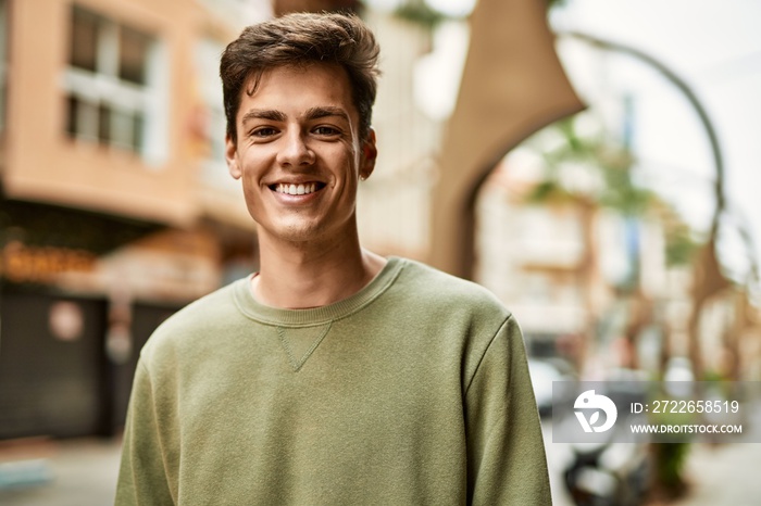 Young hispanic man smiling happy standing at the city.