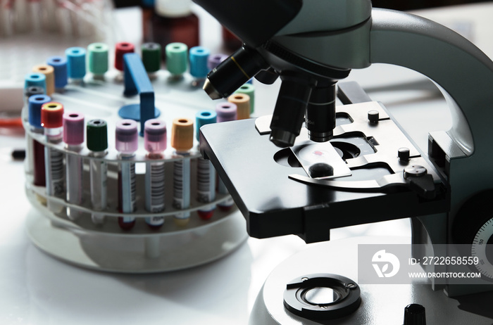 workbench of laboratory and microscope with a blood sample on the slide / laboratory work table with a microscope and blood samples