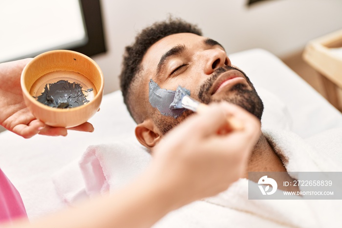 Man reciving facial treatment at beauty center.