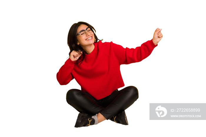 Young indian woman sitting on the floor cut out isolated dancing and having fun.