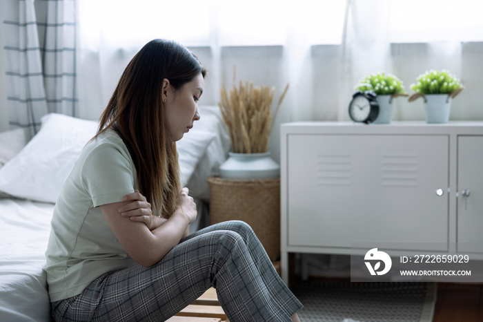 Teenage Asian girl with depression sitting alone in bedroom.