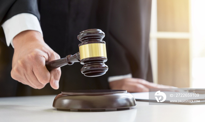 Close up of Male lawyer or judge hand’s striking the gavel on sounding block, working with Law books, report the case on table in modern office, Law and justice concept