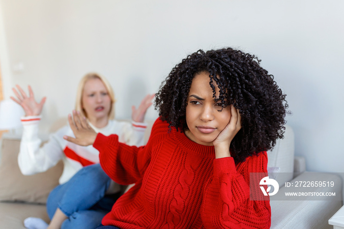 Dont want to hear. Unhappy disturbed tired woman communicating with her friend sitting near her on the sofa shaking her hands. Friends arguing on sofa at home. Two female friends arguing