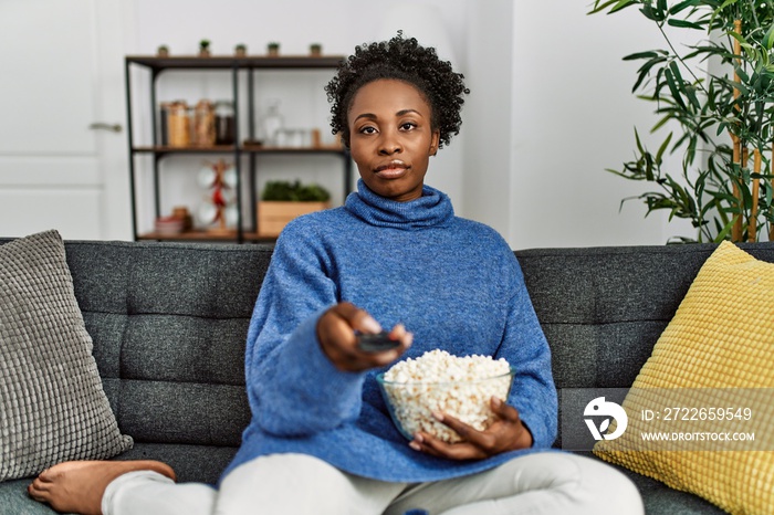 African american woman watching movie sitting on sofa at home