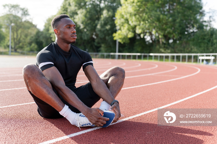 Athlete stretching legs before training at sports track