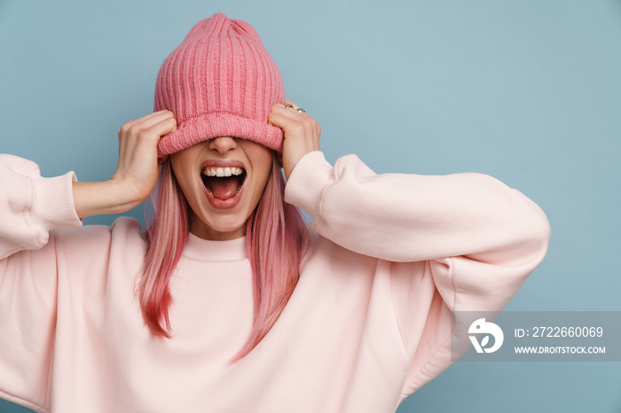 Young white woman with pink hair pulling hat down over her face