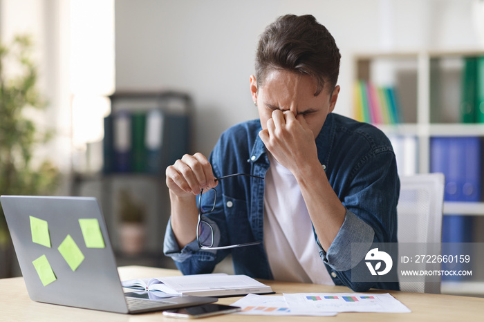 Deadline Stress. Overworked Male Entrepreneur Massaging Nosebridge At Workplace In Office