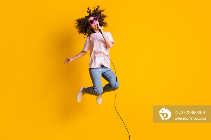 Photo portrait full body view of excited girl jumping up singing into mic isolated on vivid yellow colored background