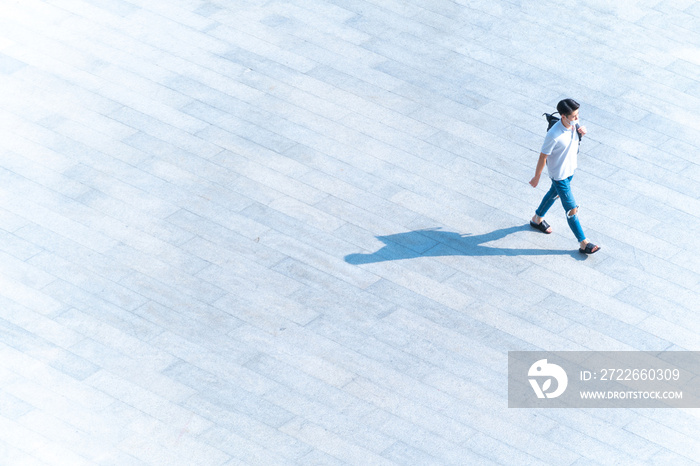 top aerial view man people with face mask walk on across pedestrian concrete with black silhouette shadow on ground, concept of social new normal life prevention of covid pandemic and air pollution.