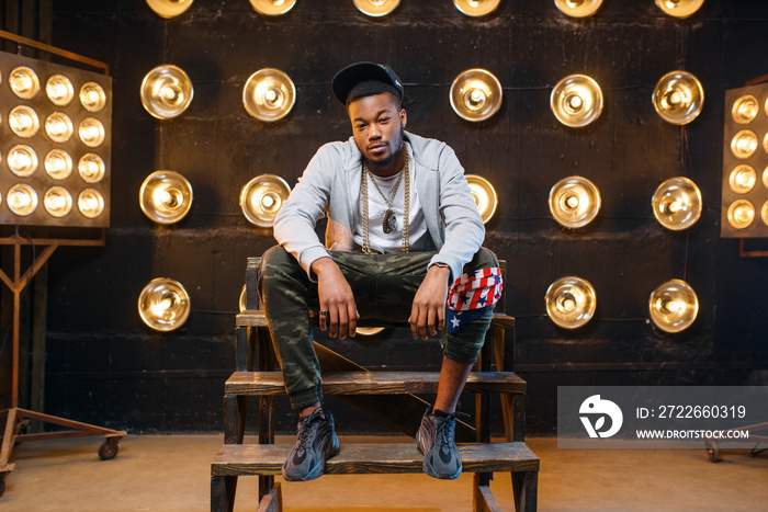 Black rapper in cap poses, perfomance on stage