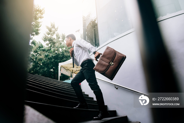 Businessman walking up on stairs and holding briefcase.