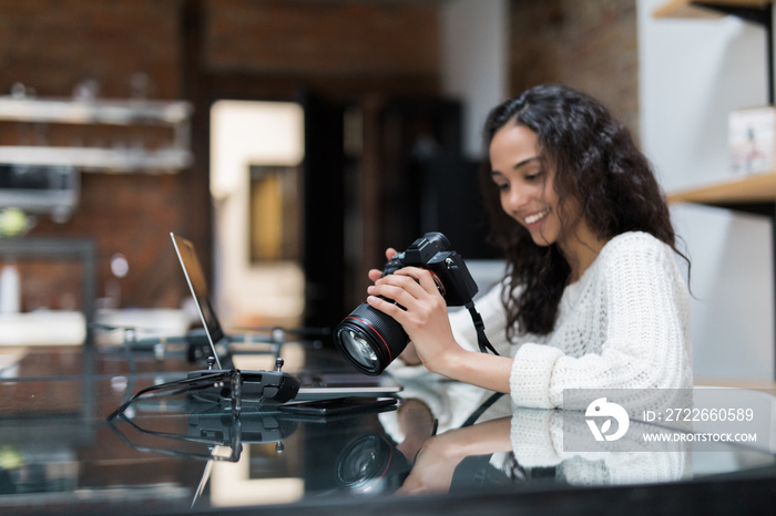 Female photographer sitting on the desk with laptop at home