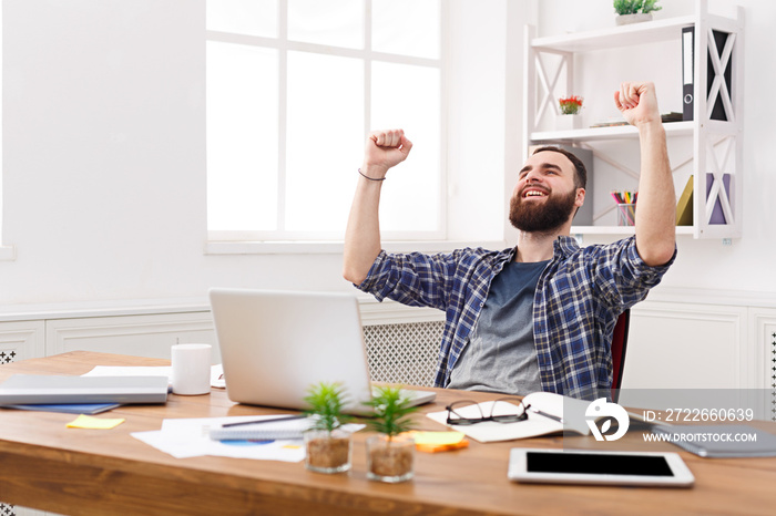 Young happy businessman in office with computer