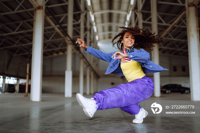 Young  woman - dancer  with american bandana dancing  in the street. Sport, dancing and urban culture concept.