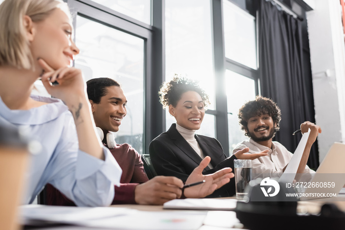 Positive multiethnic business people looking at document while working in office.