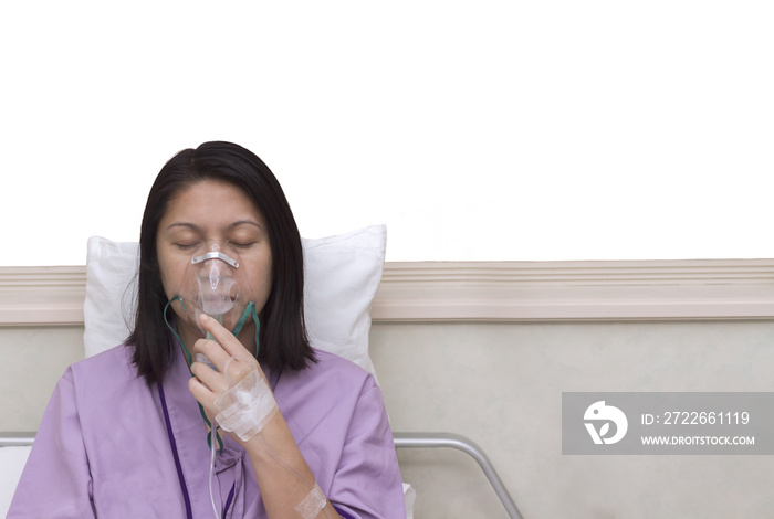 Sick beautiful female in lilac cloth hold nasal mask with respiratory problem in hospital room. Asia woman patient inhalation therapy by the mask of inhaler with soft stream smoke from bronchodilator.