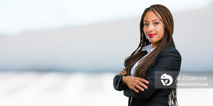 Portrait of a young black business woman crossing his arms, smiling and happy, being confident and friendly