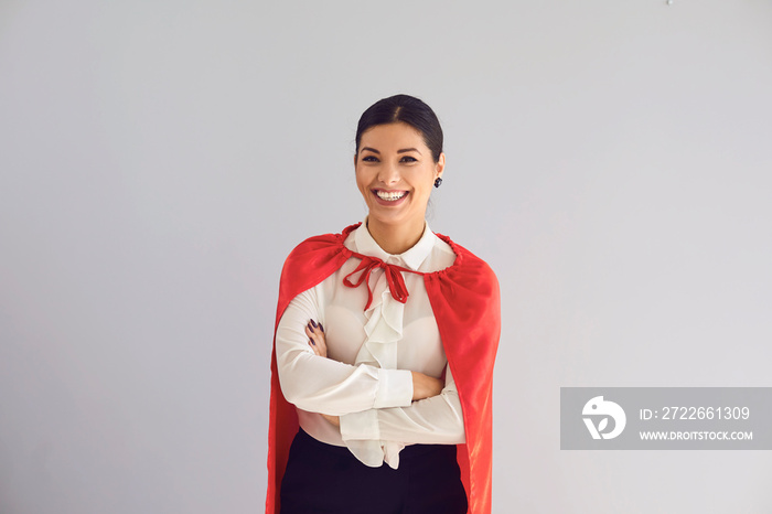 Happy woman in superhero costume laughs on gray background.