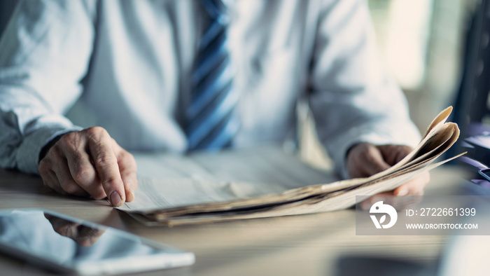 Businessman reading the newspaper on table