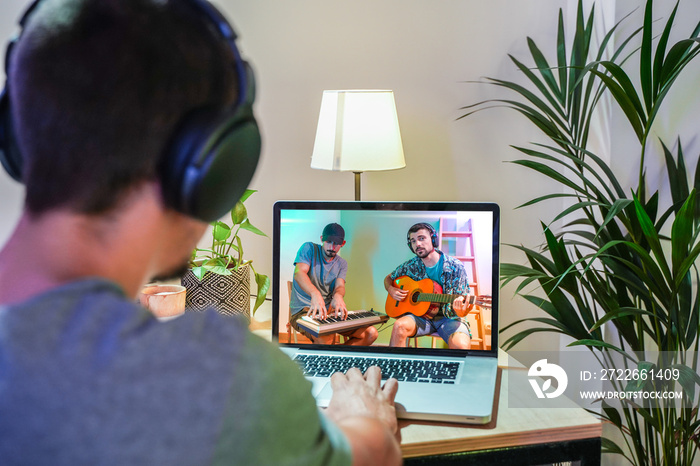 Coronavirus concept. Back view of man watching live concert video while staying at home. Close up of a man enjoying a musical concert on a laptop. Stay at home. Quarantine. Isolated.