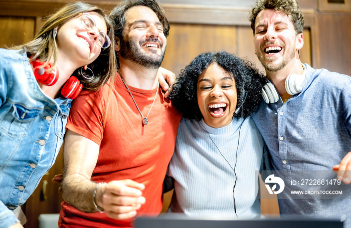 Young people students having fun laughing together with laptop at startup studio - Genz lifestyle influencer concept with multiethnic friends on video chat conference call - Vivid contrast filter