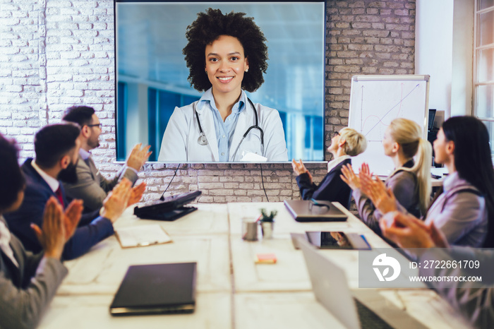 Team of business people looking doctor speech at projector screen in video conference