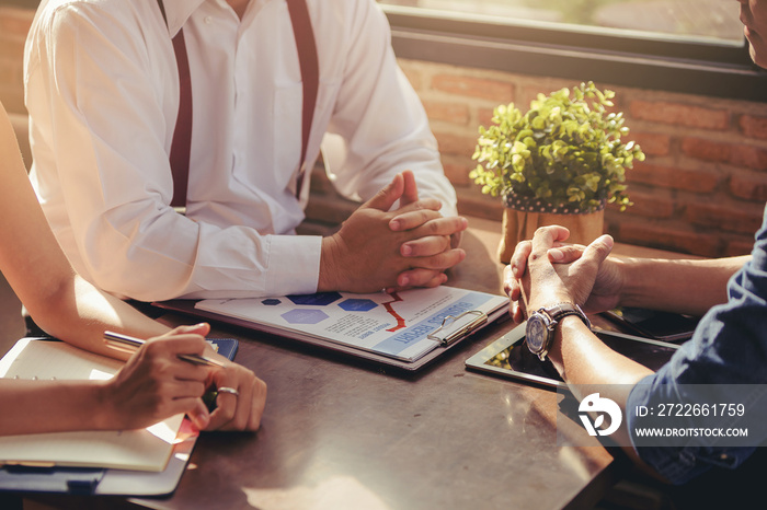 Talking about serious business. Thoughtful business peoples holding hands clasped and looking to business partner while sitting at his working place.