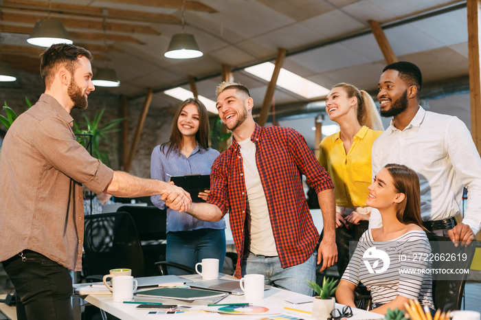 Young designers making deal with client and shaking hands