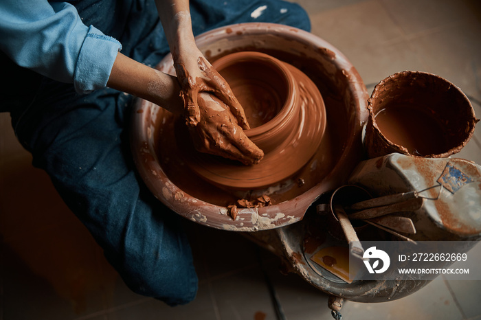 Beautiful elegant ceramicist hands shaping ceramic bowl on pottery wheel in workshop