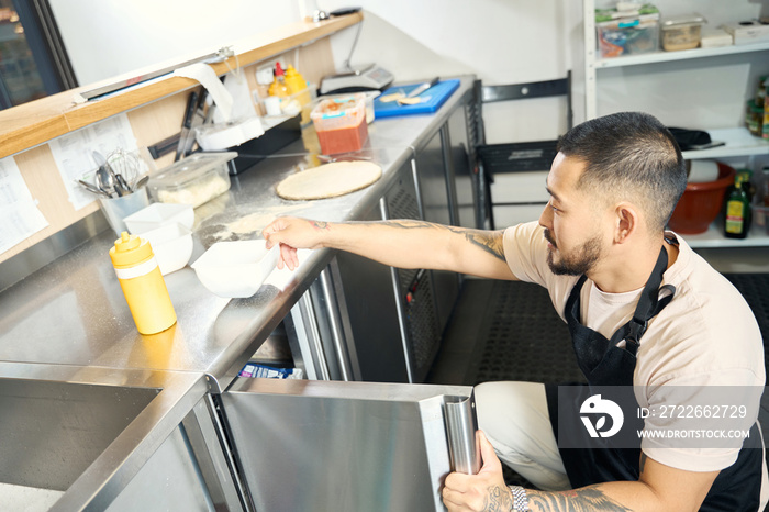 Asian guy in apron preparing his kitchen for a cook-off